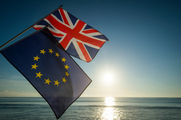 European Union and British Union Jack flags flying together as the sun rises on a new era on the relationship between the EU and UK after Brexit