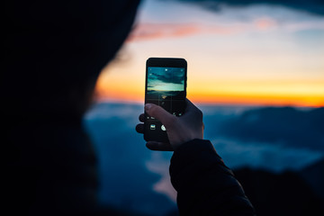  Blurred person makes picture of the sunsets with a smartphone