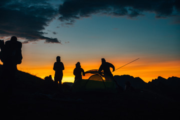 Fototapeta na wymiar People build a tent in the sunset