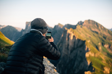  Person with iPhone makes a photographs next to a mountain ridge