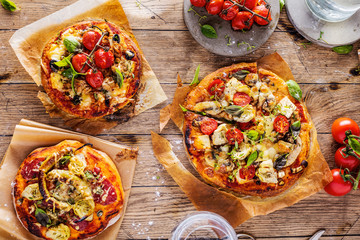 Fresh selfmade mini pizza on rustic wooden oak table 