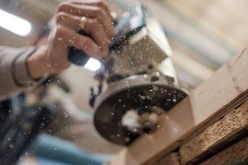 Carpenter using electric woodworking. Routing is a high speed process of cutting, trimming. Focus...