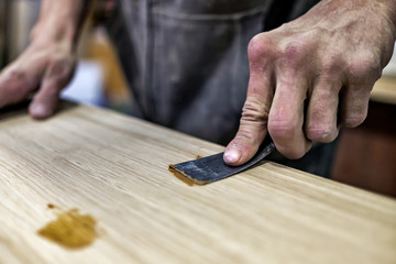 Putty knife in man hand. Removing holes from a wood surface. Preparation of boards before impregnation with varnish.