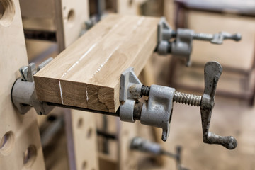 Using clamps and glue to connect wooden timbers for furniture detail. Close up view.