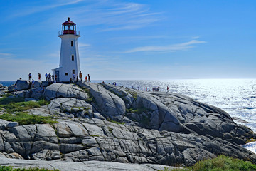 PEGGY'S COVE, NOVA SCOTIA - AUGUST 2019:  The lighthouse and the unique rock formations on which it rests are a popular attraction for visitors on the Atlantic coast. - obrazy, fototapety, plakaty