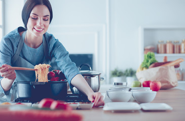 Obraz premium Cooking woman in kitchen with wooden spoon