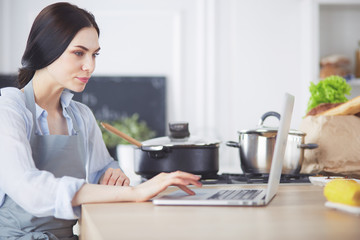 Young woman using a tablet computer to cook in her kitchen.