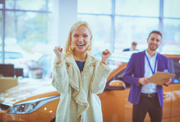 Young beautiful woman is very happy after buying a new car