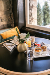 Breakfast table at hotel restaurant with flowers, quiche, blueberry muffin, and fruit, modern restaurant table