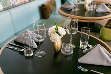 Nice table setting at restaurant with napkins, flowers, silverware, and wine glasses, trendy restaurant 