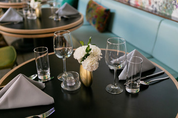 Nice table setting at restaurant with napkins, flowers, silverware, and wine glasses, trendy restaurant 