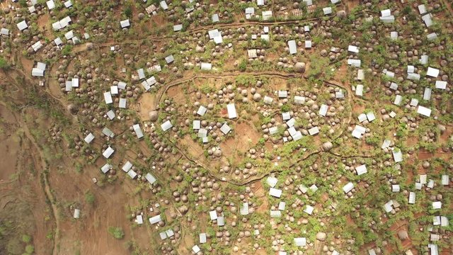 Overhead aerial view flying over remote hilltop settlement in Konso, traditional houses and huts in developing country Ethiopia, village life in rural Africa