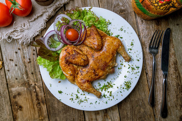 fried chicken tobacco on white plate on wooden table. Georgian cuisine
