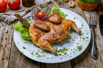 fried chicken tobacco on white plate on wooden table. Georgian cuisine