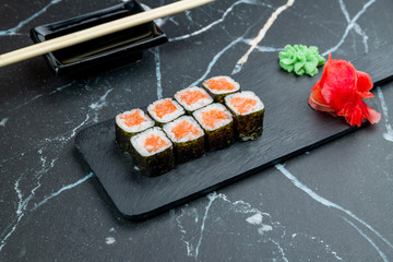 Maki roll with salmon on dark marble table