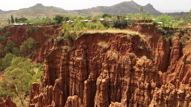 Flying past peculiar eroded pillars reveals remote village built on sandstone cliffs in South Ethiopia, rural landscapes Africa