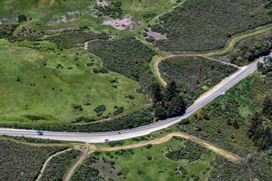Aerial View of an Isolated Rural Highway Cutting through the Green Mountains and Farms in San Mateo County, California, USA