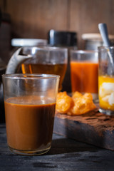 Traditional Thai hot coffee with milk on the wood table there are Traditional Thai hot tea with milk, deep-fried doughstick (patongko), hot tea and soft-boiled egg plated around.