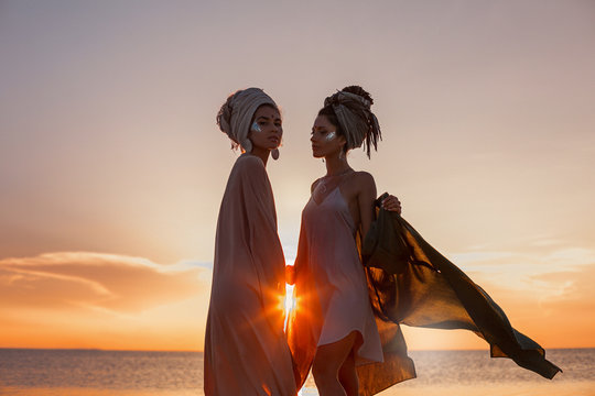 silhouette of two young beautiful girls in turban on the beach at sunset