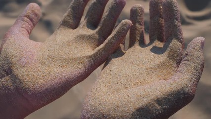 Sand in the hands. Close up view of sand running through a hands. Slow motion.