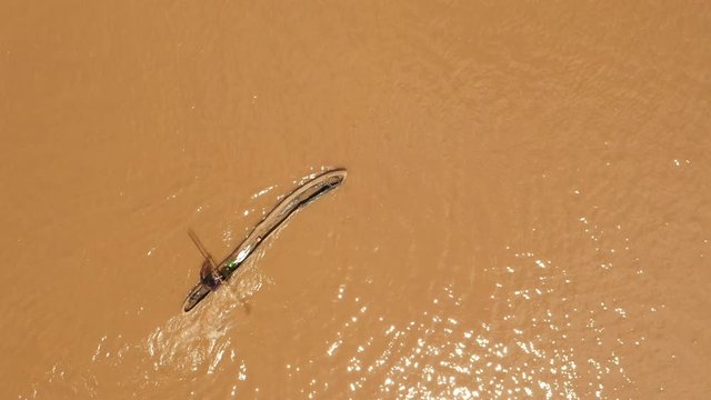Overhead drone shot of local fisherman paddling on Omo river in classic hollowed dugout canoe in Ethiopia, employment in rural Africa