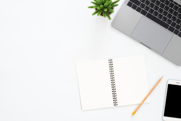Creative flat lay photo of workspace desk. Top view office desk with laptop, phone, pencil, notebook and plant on white color background. Top view with copy space, flat lay photography.