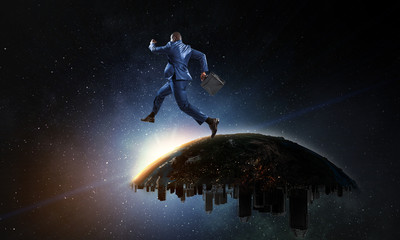 Obraz na płótnie Canvas Back view of a black businessman jumping and running from urban Earth planet into starry space