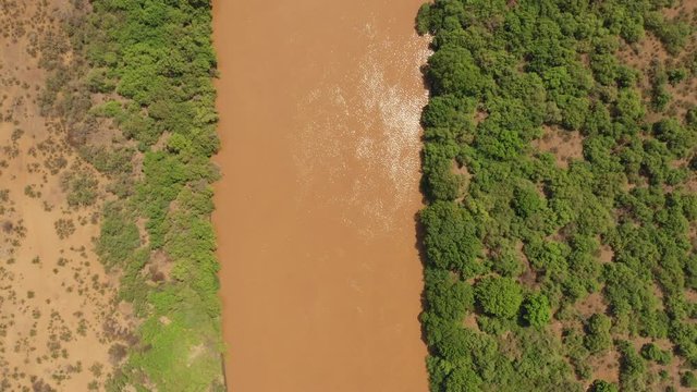Overhead drone shot of red brown colored water of the Omo river in Ethiopia, near the border crossing with Kenya