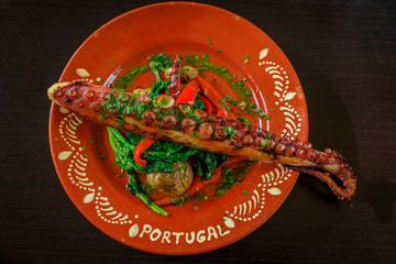 Grilled octopus tentacle Portuguese style with spinach, red peppers and potatoes at an al fresco restaurant in Porto