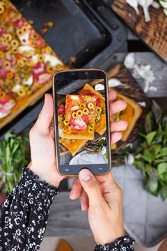 Phone food photography of handmade pizza. Hands holds smartphone.