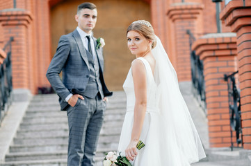 Fototapeta premium Portrait of young wedding couple are walking in the forest and admire nature and look at the landscape. Wedding ceremony and photo shoot outdoors. Newlyweds.