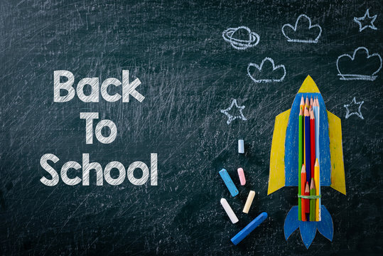 Education or back to school Concept. Top view of Painted paper rocket with colorful of color pencil and chalk on chalkboard background. Flat lay.