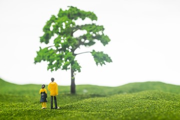 Love nature concept: Miniature couple figures in front of a tree