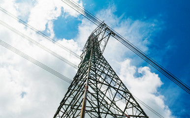 Electricity pylons with blue sky and white clouds. High voltage grid tower with wire cable at distribution station. High voltage electric tower and transmission lines.