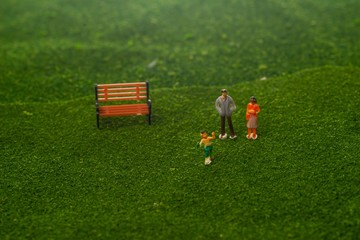 Obraz na płótnie Canvas Happy family concept: Miniature family figurines on a park. Selective focusing