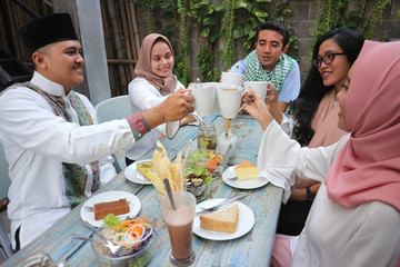 group of friends having tea toast at table dining during ramadan celebration