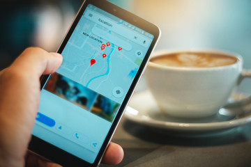 The tourist drink coffee in cafe and using smartphone search for a location to travel
