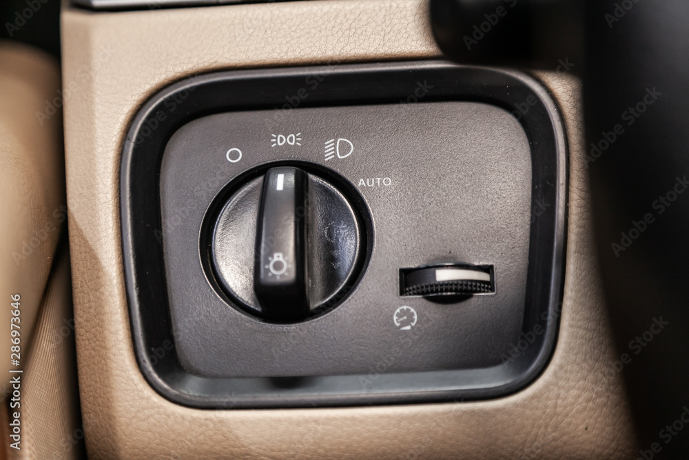 Poster close-up on the headlight switch control buttons, automatic adjust level dashboard. modern car inter