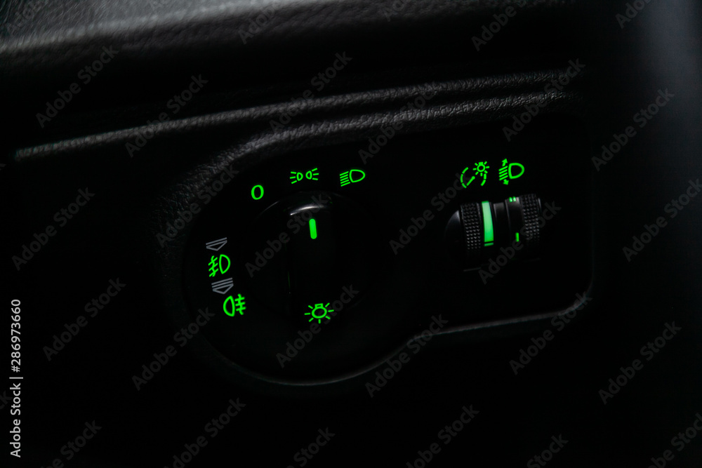 Poster close-up on the headlight switch control buttons, automatic adjust level dashboard. modern car inter