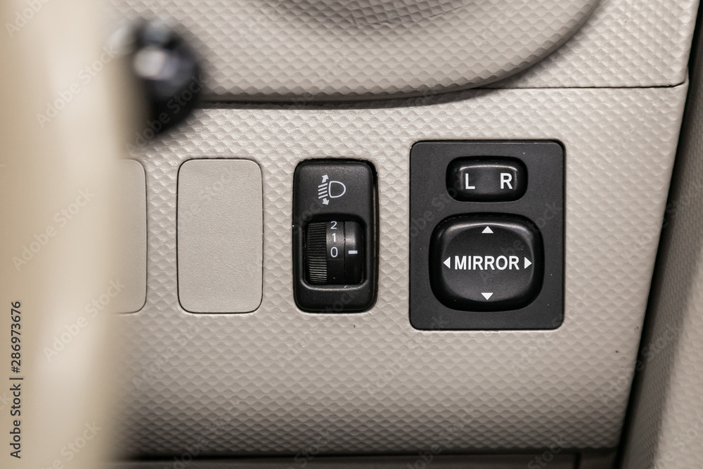 Poster close-up on the headlight and side mirror switch control buttons, automatic adjust level dashboard. 