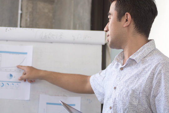 young atractive asian man presenting graphic cart at white board