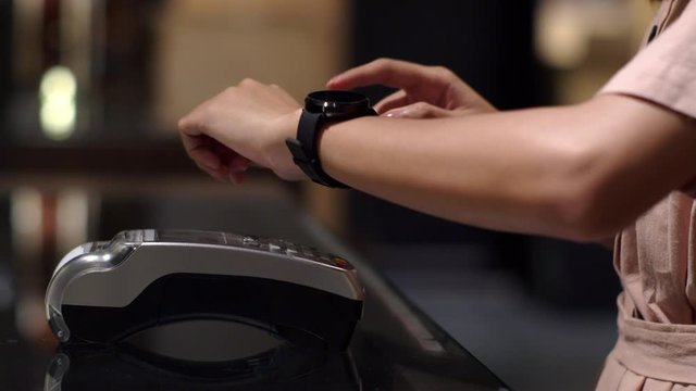 Young woman using smart watch to express pay on counter