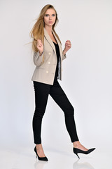 Vertical portrait of a pretty beautiful girl, a happy young woman manager in a jacket and black pants on a white background in studio. Smiling, showing emotions.