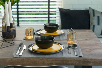dining table with black and yellow plate setting in modern home.