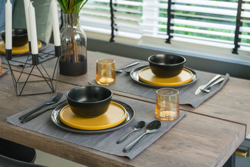 dining table with black and yellow plate setting in modern home.