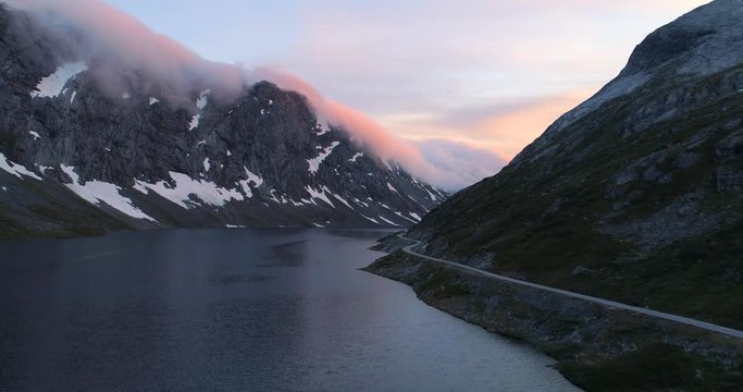 Aerial: Drone footage of beautiful fjord along mountain range and road against sky - Geiranger Fjord, Norway