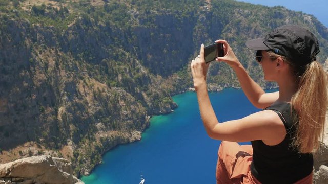 Woman traveller taking picture or video and enjoying beautiful view of The Butterfly Valley from the top of the mountain