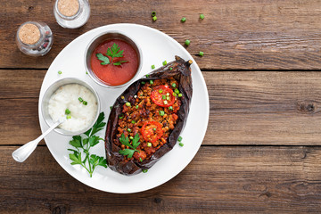 Karniyarik - Stuffed Eggplants, Aubergines with minced meat and vegetables baked with tomato sauce served on a plate.