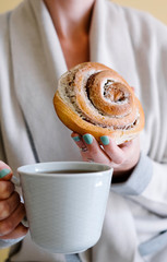 A woman having her morning coffee  and cinnamon rolls