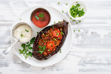 Karniyarik - Stuffed Eggplants, Aubergines with minced meat and vegetables baked with tomato sauce served on a plate.